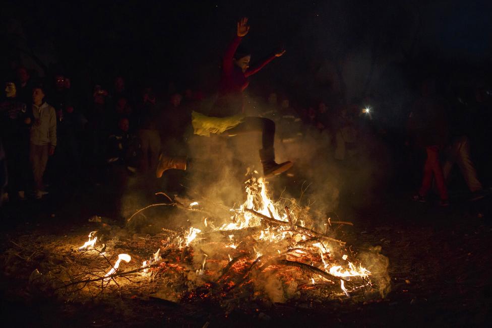 a girl jumps over the fire during the "the burial of the sardine" funeral procession, which marks the end of carnival festivities, in madrid