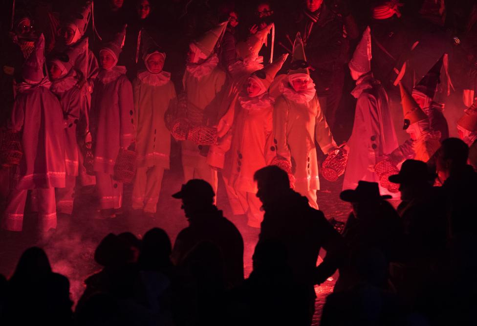 children dressed as pierrot dance around flares during the rondeau at the carnival event in binche