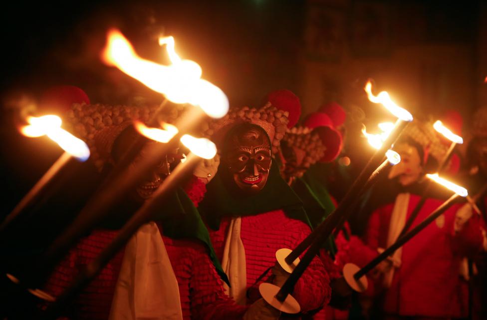 revellers in traditional costumes and carnival masks parade through the village of elzach in the black forest