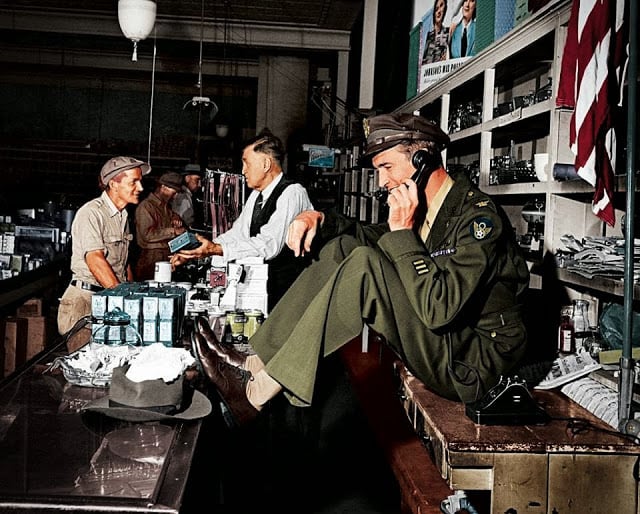 while his father chats with a customer at the hardware store, a uniformed jimmy stewart sets up a date to go fishing,1945. (colorized by john gulizia from america)