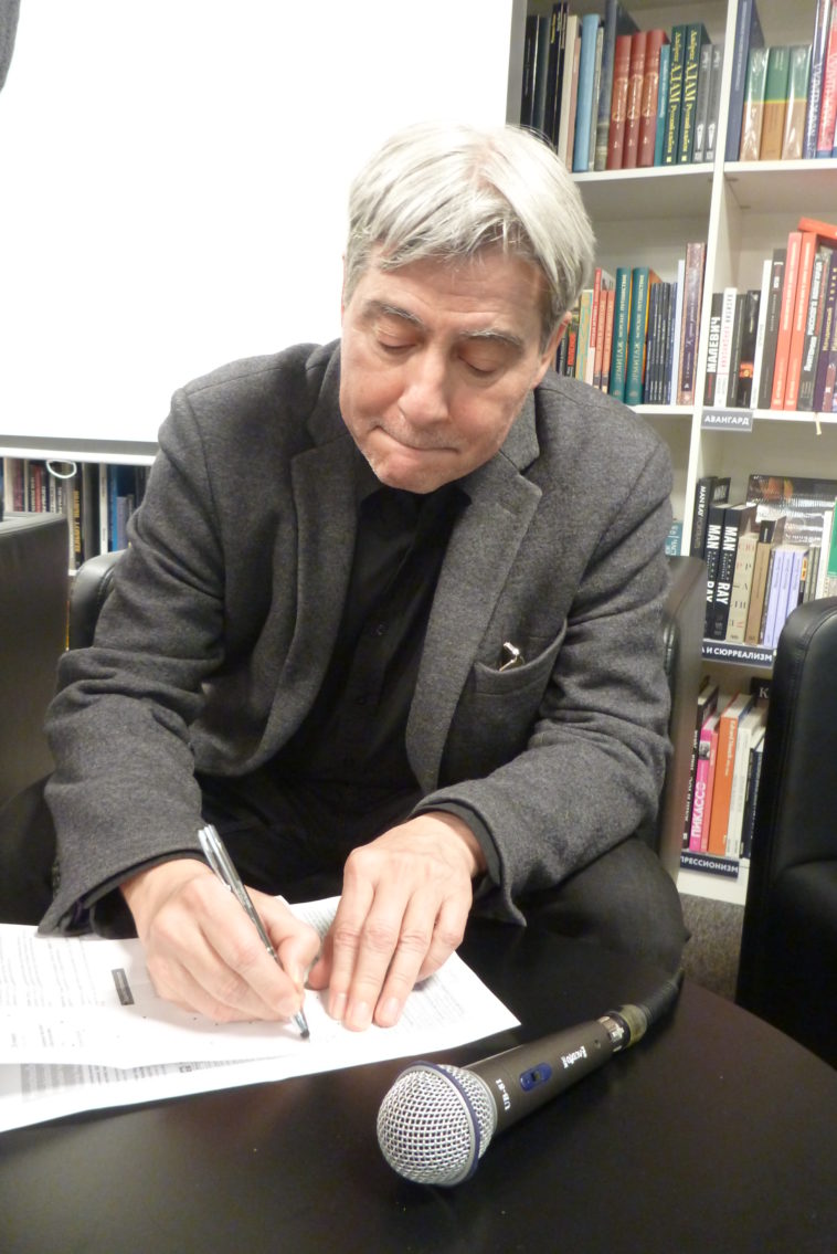 a man sitting at a desk in front of a book shelf