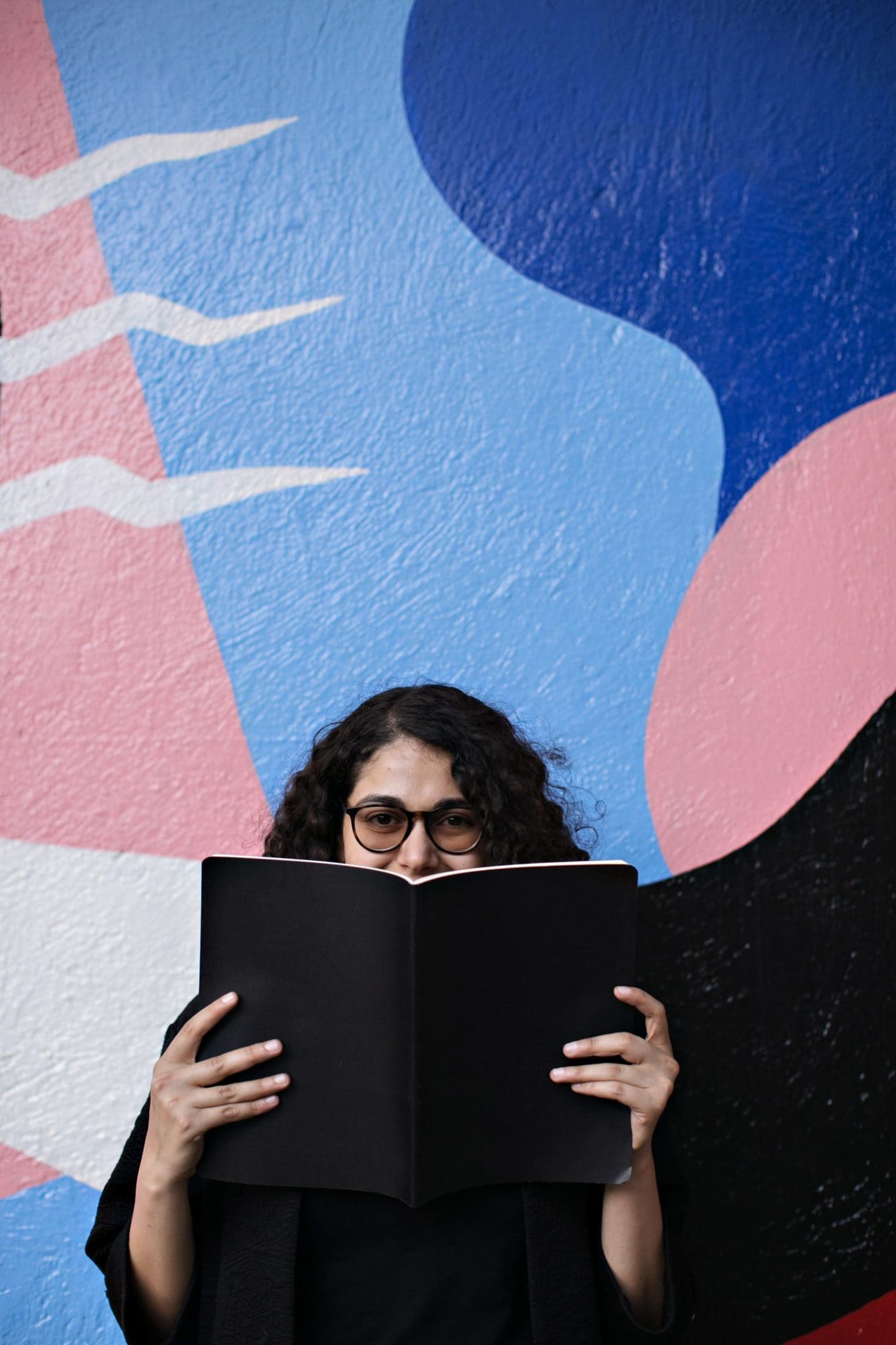 woman standing and holding open book covering her mouth