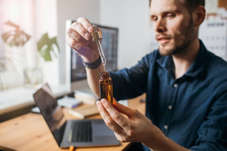 Vitamins and supplements. Hand holding pipette of Hemp oil. Close up man uses CBD oil. Medical cannabis. Healthy lifestyle