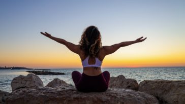 woman sitting on the stone in front of the ocean