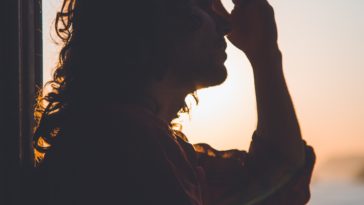 man holding forehead under sunset