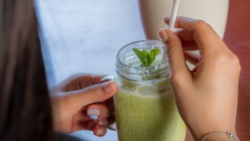 person holding clear drinking glass with green liquid