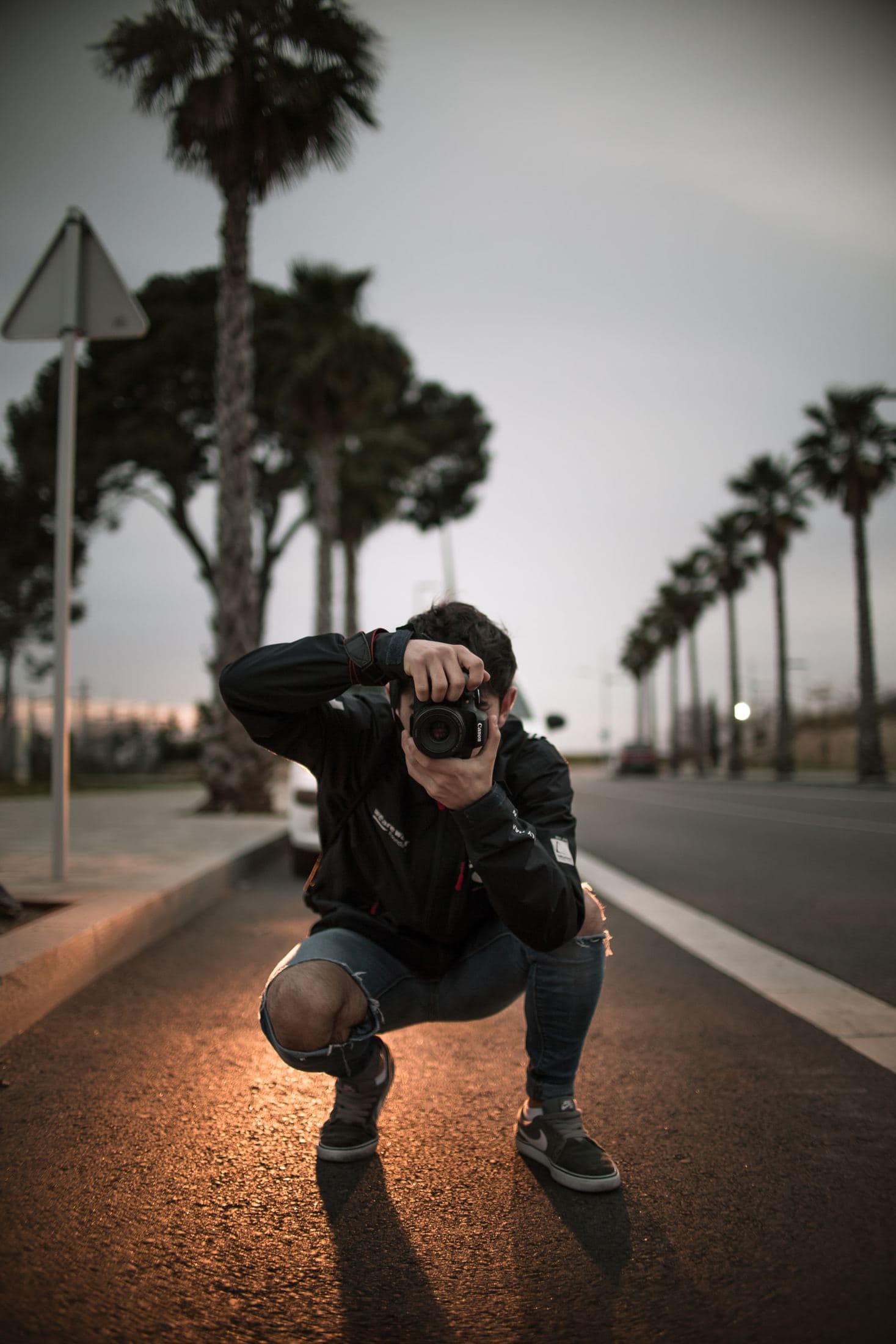 man wearing blue ripped jeans holding dslr camera