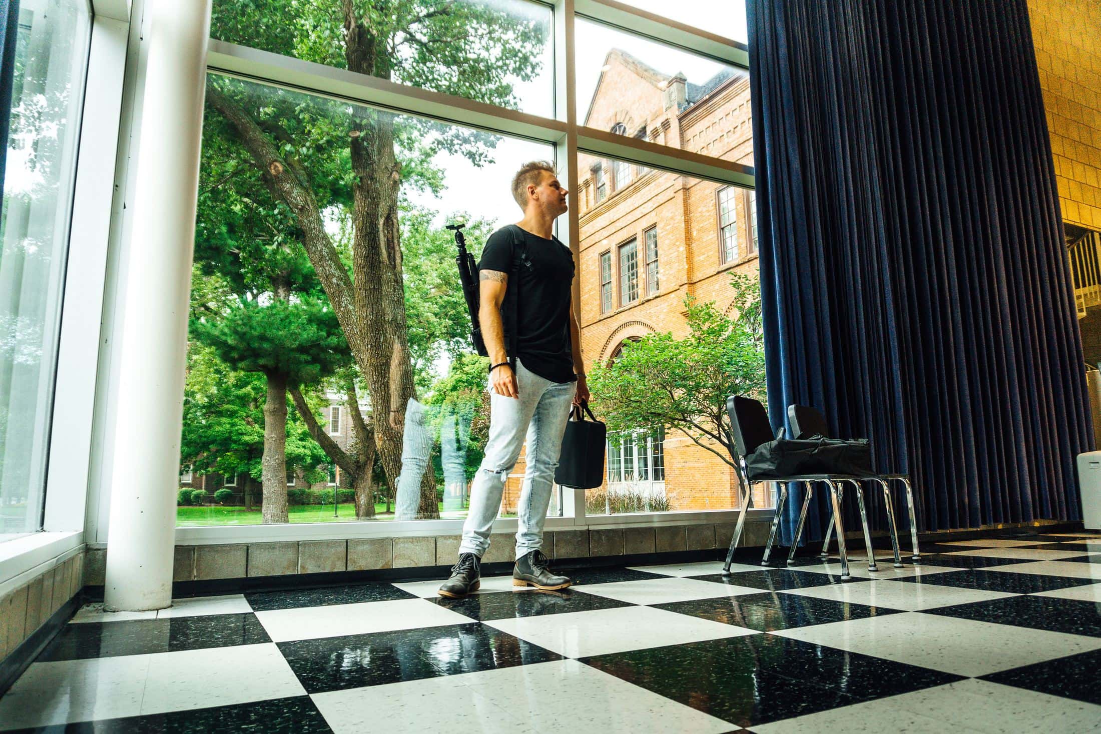 woman in black t-shirt and white pants standing near glass window