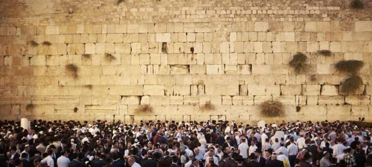 a group of people standing in front of a crowd with western wall in the background