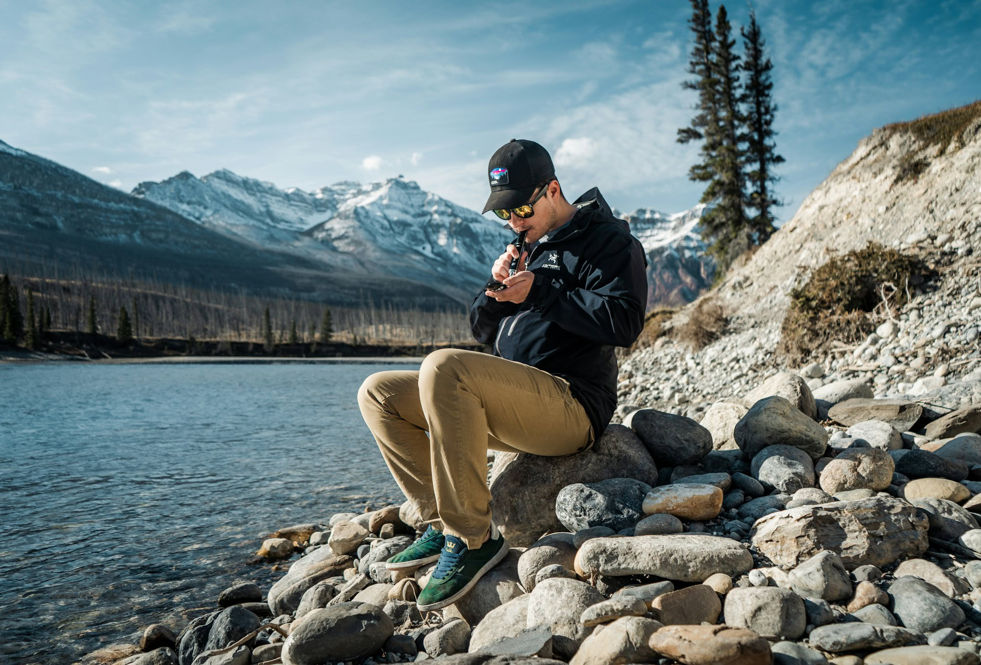 Exploring the World with Ease: How Portable Vaporizers Enhance Travel Experiences a man sitting on a rock by a lake