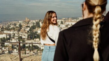 a woman standing next to a man on top of a hill