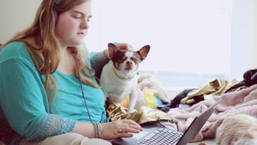 girl in blue jacket holding white and brown short coated puppy