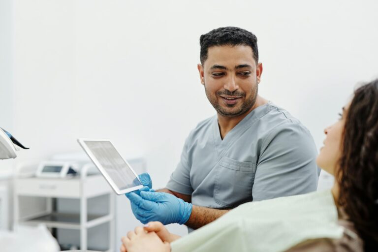 Nurse uses digital tablet for patient consultation and diagnosis in a clinical setting.