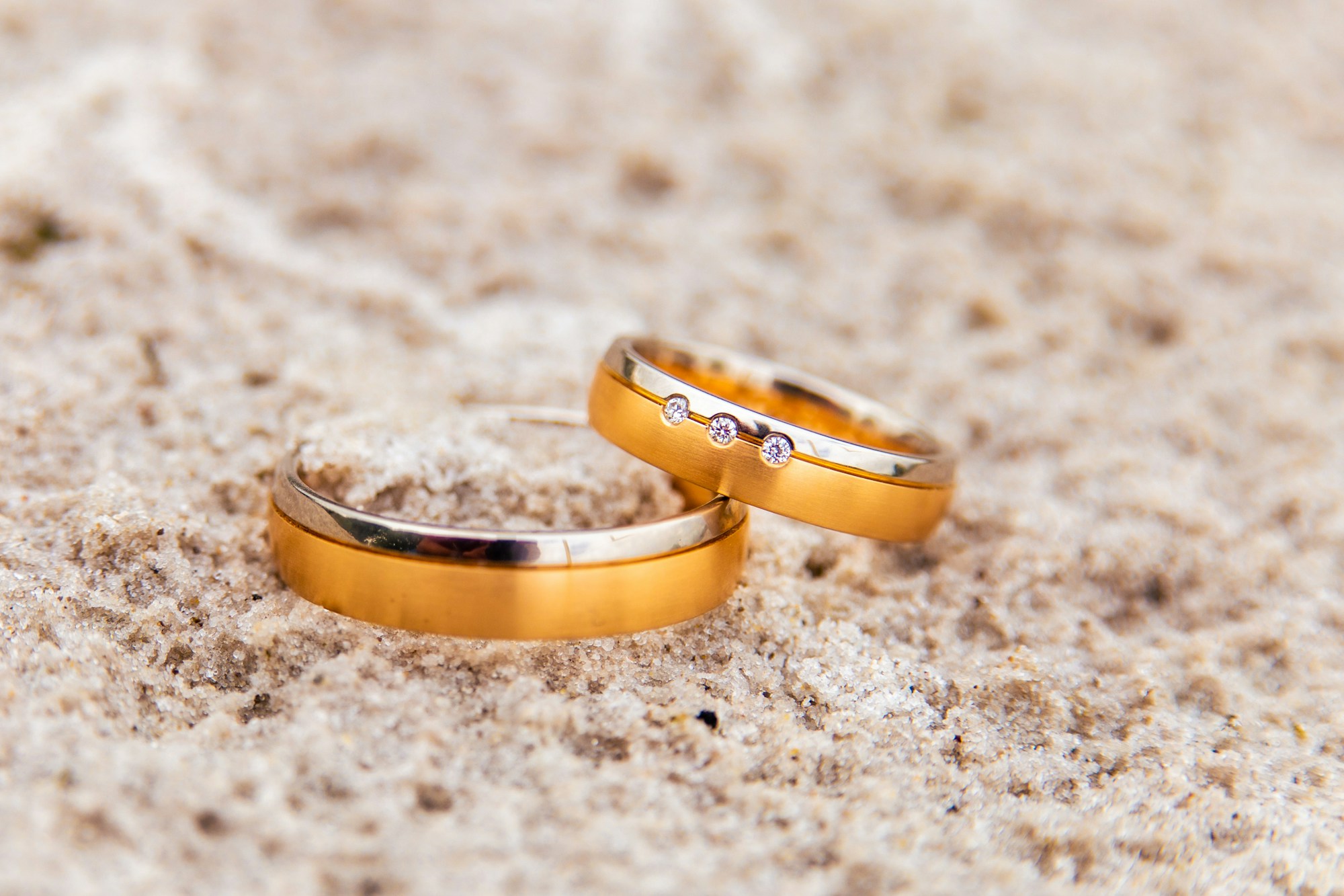 Why Are Elegant Classic Wedding Bands a Popular Choice? two gold wedding rings laying on the sand