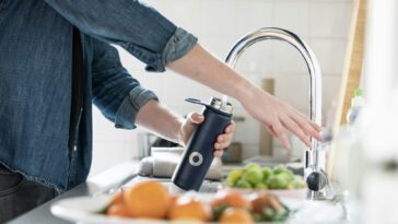 person in blue denim jacket holding stainless steel bottle