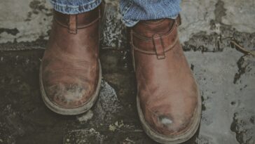 person in brown leather boots on grey concrete pavement