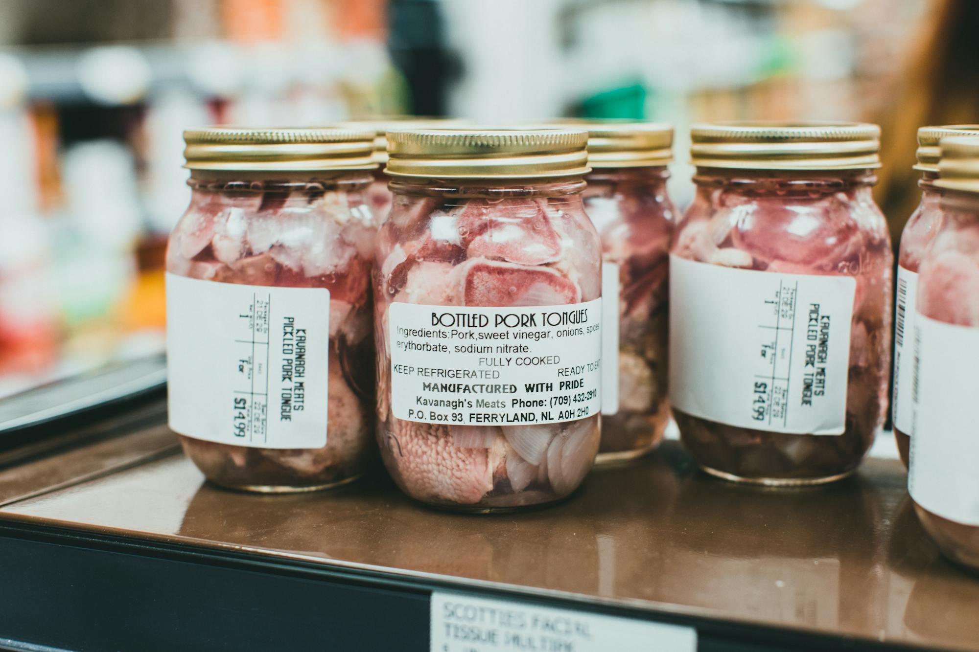 10 Best Meat Preservation Methods: Traditional & Modern Techniques Explained detailed close-up shot of bottled pork tongues on display in a supermarket.