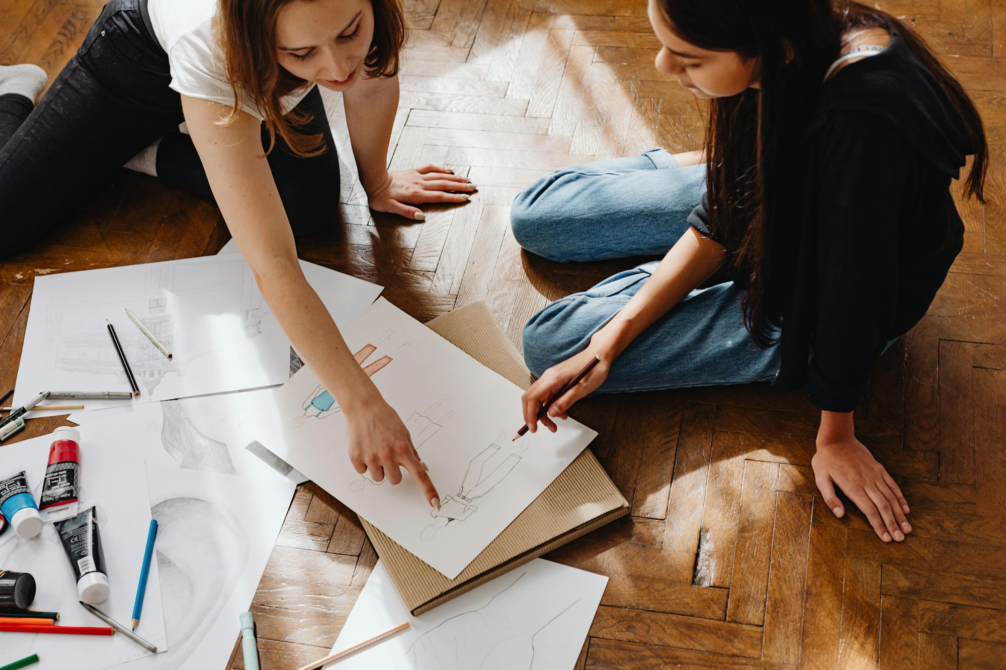 How I built a design portfolio that actually gets clients (not just likes) two young women collaborating on fashion designs, sharing ideas and sketches.